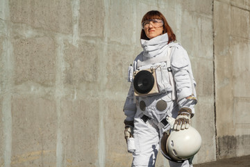 Beautiful girl astronaut without a helmet on the background of a gray wall. Fantastic space suit. © Andriy