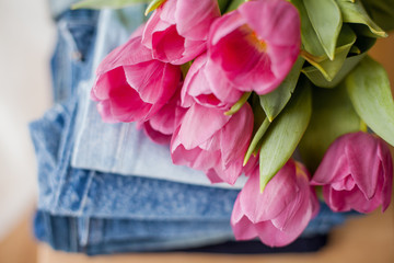 A bouquet of tulips lying on a pile of jeans. Clothing.