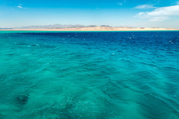 Seascape, view of the blue sea with high bald mountains in the background