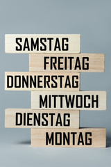 A list of wooden blocks lying on top of each other with a list of days of the six-day work week in...