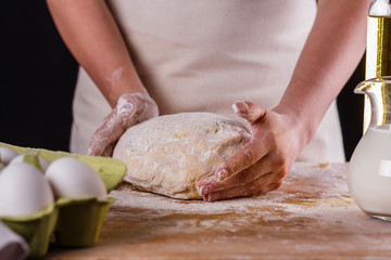 Fototapeta premium young woman in apron kneading dough on board