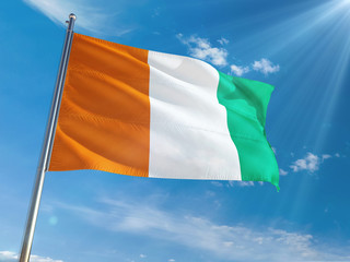 Cote D'Ivoire National Flag Waving on pole against sunny blue sky background. High Definition