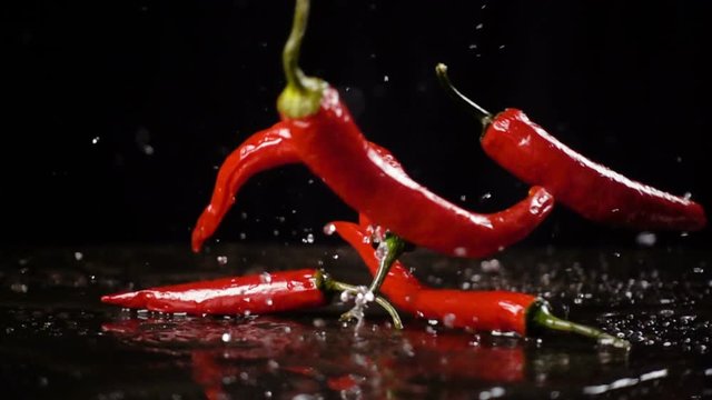 Falling red  chili pepper with water splash, slow motion