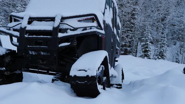 Off road vehicle with tracks covered in snow.