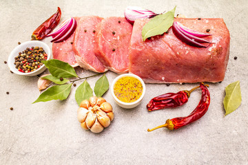 Raw pork tenderloin with vegetables and spices. Cooking meat background, fresh brisket boneless steak on stone background.