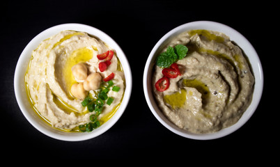 Hummus and babaganoush on black background.