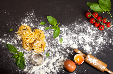 Italian traditional raw pasta on the black stone background, top view