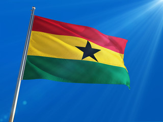 Ghana National Flag Waving on pole against deep blue sky background. High Definition