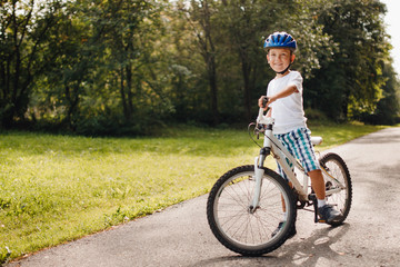 Little boy in helmet learning lessons riding bicycle.