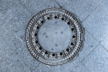 Manhole cover in tiled pavemant