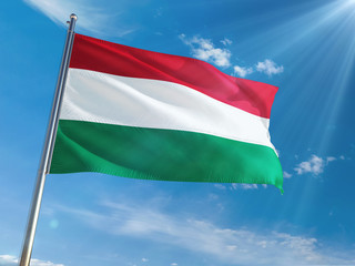 Fototapeta na wymiar Hungary National Flag Waving on pole against sunny blue sky background. High Definition