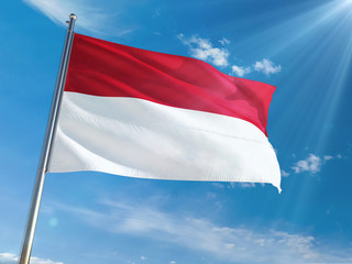 Fototapeta na wymiar Indonesia National Flag Waving on pole against sunny blue sky background. High Definition