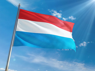 Luxembourg National Flag Waving on pole against sunny blue sky background. High Definition