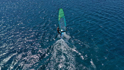 Aerial top view photo of fit man practising wind surfing in exotic open ocean bay with crystal clear emerald sea