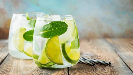 Two Mojito cocktail with ice cubes in a glass on a rustic table, selective focus. With copy space