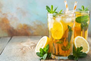 Traditional iced tea with lemon and ice in tall glasses on a wooden rustic table. With copy space