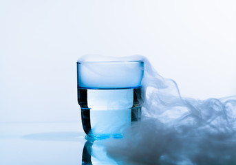Glass of water on a blue background. Water  into glass on   smoky background