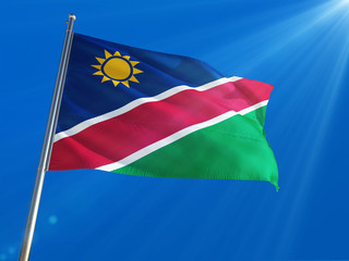 Obraz premium Namibia National Flag Waving on pole against deep blue sky background. High Definition
