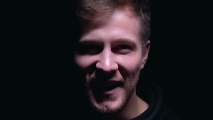 Psychopathic man laughing isolated on dark background, lunatic asylum, madness