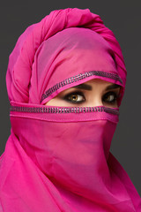 Fototapeta premium Close-up shot of a young charming woman wearing the pink hijab decorated with sequins. Arabic style.