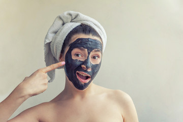 Beauty portrait of woman in towel on head applying black nourishing mask on face, white background isolated. Skincare cleansing eco organic cosmetic spa relax concept