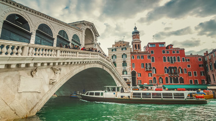 Fototapeta na wymiar Vaporetto passes underneath Rialto Bridge. The bridge is oldest bridge crossing the Grand Canal in Venice, Italy