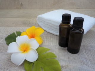 夏のリラクゼーションのイメージ（プルメリアの花、アロマオイルのボトル、白いタオル）