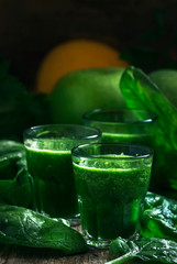 Green spinach detox smoothies with apples and lemon in glasses, selective focus