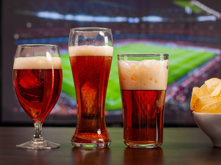 Beer glasses and chips in front of tv, football at home