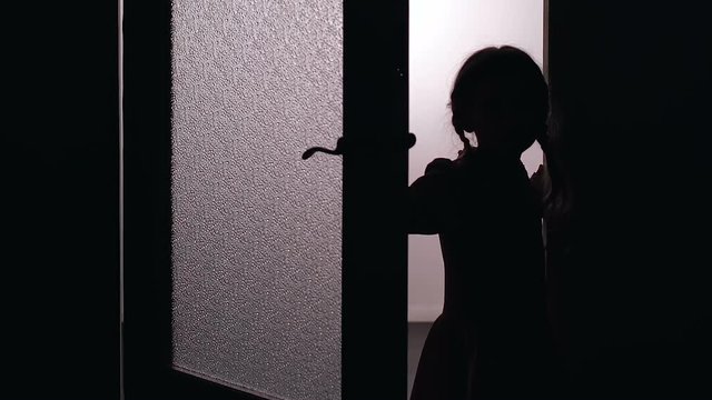 Little girl opening door into dark room, checking strange noise, house robbery