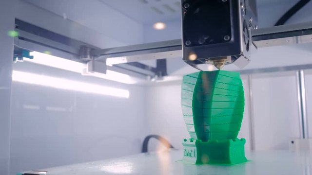 Automatic three dimensional printer machine printing plastic model of building at modern technology exhibition. 3D printing, architecture, additive technologies and 4.0 industrial revolution concept