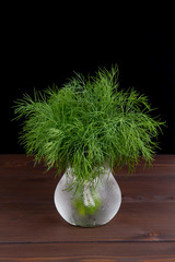green fresh dill in a glass with water on a black  background