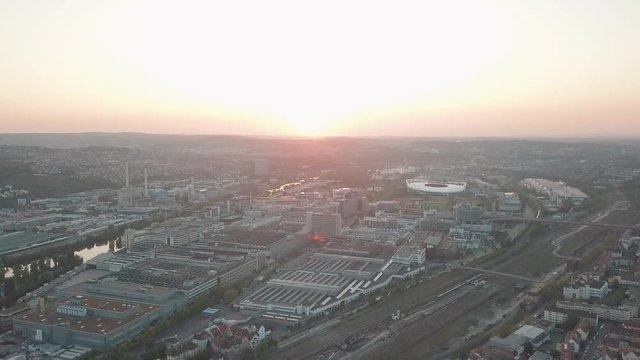 Aerial drone shot of beautiful Stuttgart, Germany while sunset with the Mercedes Benz Arena, the famous Volksfest Wasen and a lot of industry in the foreground and Stuttgart Downtown in the background