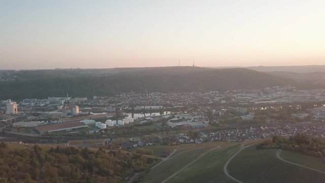 Aerial drone shot of beautiful Stuttgart, Germany while sunset with the Mercedes Benz Arena, the famous Volksfest Wasen and a lot of industry in the foreground and Stuttgart Downtown in the background