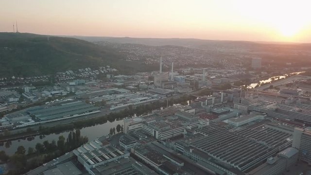 Aerial drone shot of beautiful Stuttgart, Germany while sunset with the Mercedes Benz Arena, the famous Volksfest Wasen and a lot of industry in the foreground and Stuttgart Downtown in the background