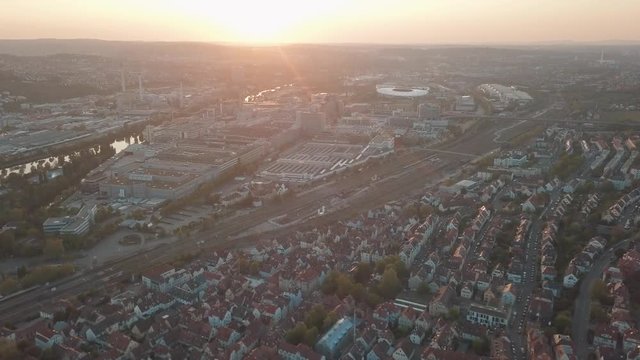 Aerial drone shot of beautiful Stuttgart, Germany while sunset with the Mercedes Benz Arena, the famous Volksfest Wasen and a lot of industry in the foreground and Stuttgart Downtown in the background