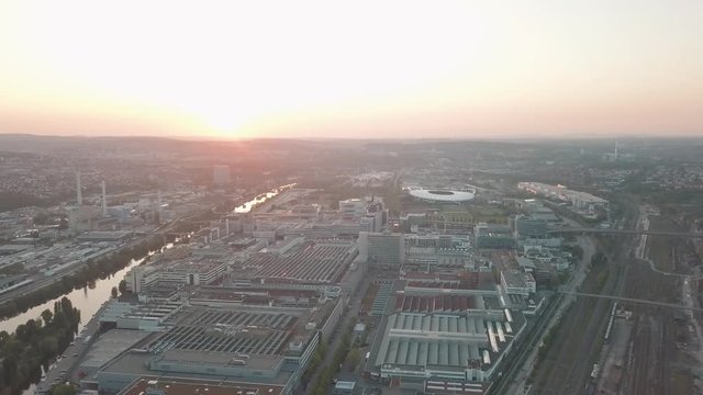 Aerial drone shot of beautiful Stuttgart, Germany while sunset with the Mercedes Benz Arena, the famous Volksfest Wasen and a lot of industry in the foreground and Stuttgart Downtown in the background