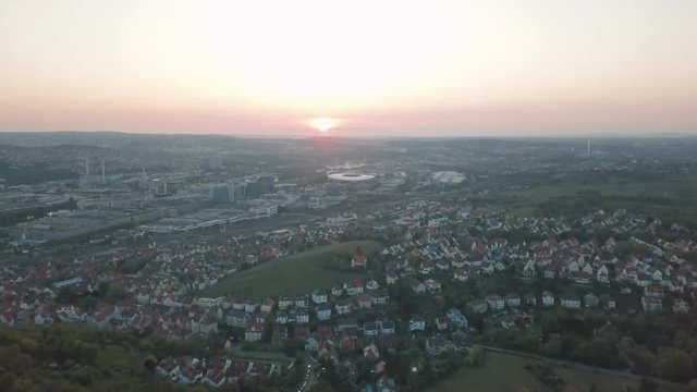 Aerial drone shot of beautiful Stuttgart, Germany while sunset with the Mercedes Benz Arena, the famous Volksfest Wasen and a lot of industry in the foreground and Stuttgart Downtown in the background