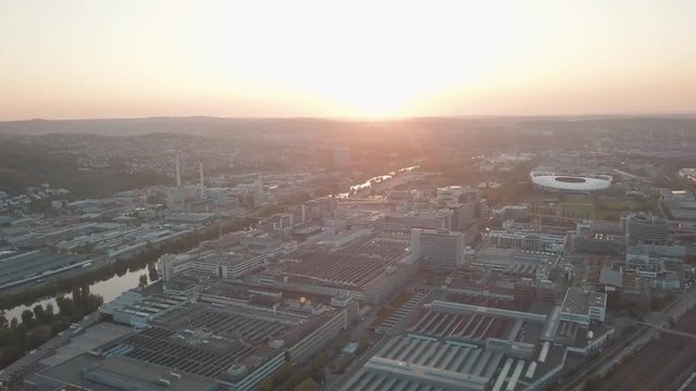 Aerial drone shot of beautiful Stuttgart, Germany while sunset with the Mercedes Benz Arena, the famous Volksfest Wasen and a lot of industry in the foreground and Stuttgart Downtown in the background