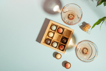 Champagne or wine in elegant glasses, a box of chocolates on a blue background. Copy space. Flat layout top view.