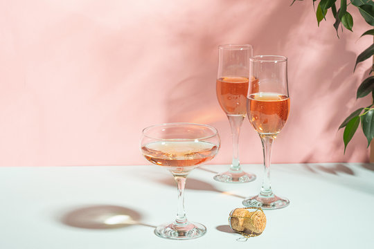 Various glasses of champagne or wine on a delicate pink background bright light. Festive concept. Copy space.