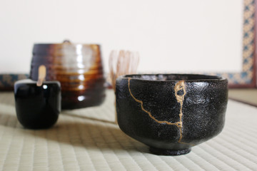 Kintsugi : Repair of crack pottery tea cup on tamami blur background