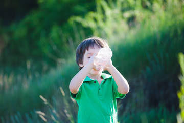 The child drinks water from a bottle