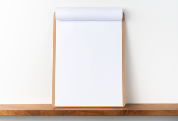 white flipped paper on clipboard on bookshelf