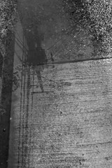 Amazing street view after a rainy day on Puerto Varas town, Chile, power lines and tower reflections in water on a puddle at a dirt road. An urban abstract textured view of the street pavement water
