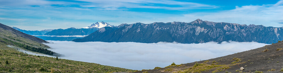 Amazing panoramic view from Osorno Volcano to an awe sea of clouds scenery on an amazing forest with Patagonia mountain range on the far distance dominated by Cerro Tronador mountain on the left