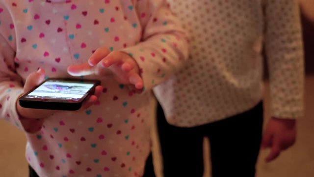 Front view of toddler swiping through pictures on a cellphone.