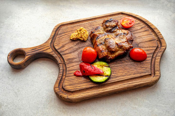 Grilled meat with vegetables on a wooden board used as a fancy plate