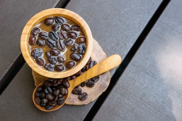 Fototapeta premium A coffee bean on a wooden cup of coffee and wooden spoon