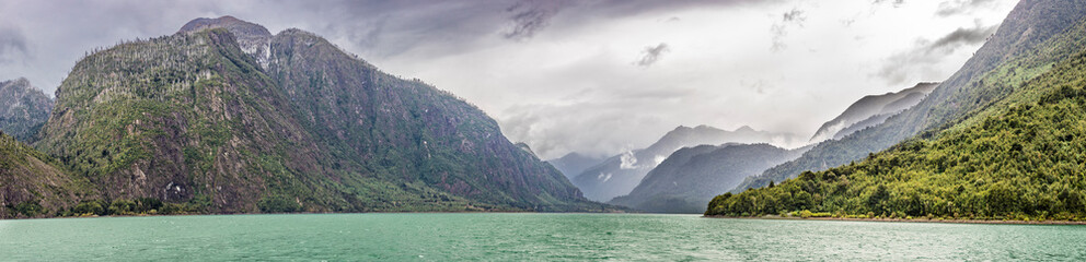 A dramatic view of North Patagonia landscapes, bad autumn weather with an overcast stormy day bringing rain to this amazing scenery. An awe boat trip around Tagua Tagua Lake turquoise waters